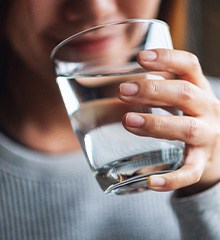 Woman in great sweatshirt drinking from glass of water
