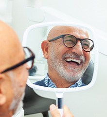 Man’s reflection in dental mirror smiling at results