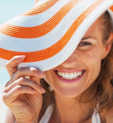 Woman in a floppy beach hat smiling brightly