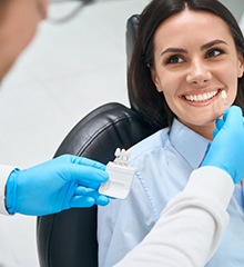 a patient smiling while her dentist picks a tooth color