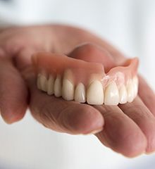 Hand holding a full denture in Farmington