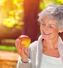Senior woman holding apple and smiling