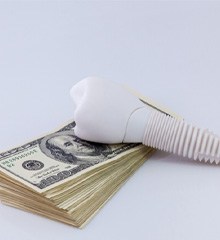 smiling implant dentist holding a piggy bank