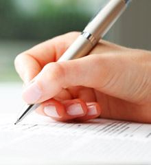 A person using a pen to fill out information concerning dental insurance in Farmington