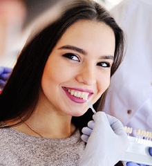 Dentist color matching veneer to patient’s tooth