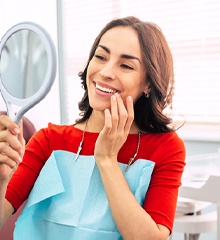 Woman admiring her veneers in hand mirror