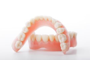 Set of upper and lower dentures with white background.