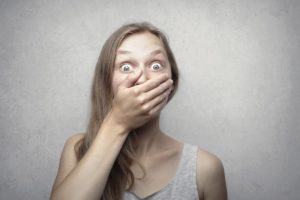 Shocked woman with hand over mouth